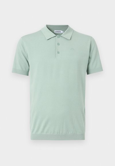 Polo à manches courtes vert clair avec trois boutons et un col, orné d'une broderie discrète du logo sur le côté gauche de la poitrine.