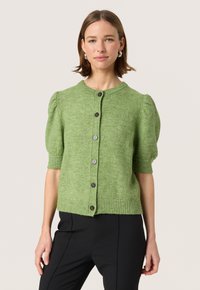 Grøn strikket cardigan med korte puffærmer, rund halsudskæring og fem mørke knapper. Ribkant i nederste kant og ærmer tilføjer tekstur.