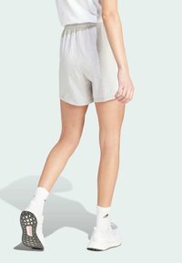 Shorts griș dintr-un amestec de bumbac, cu un brâu elastic, având un design casual. Modelul poartă șosete albe și pantofi sport.