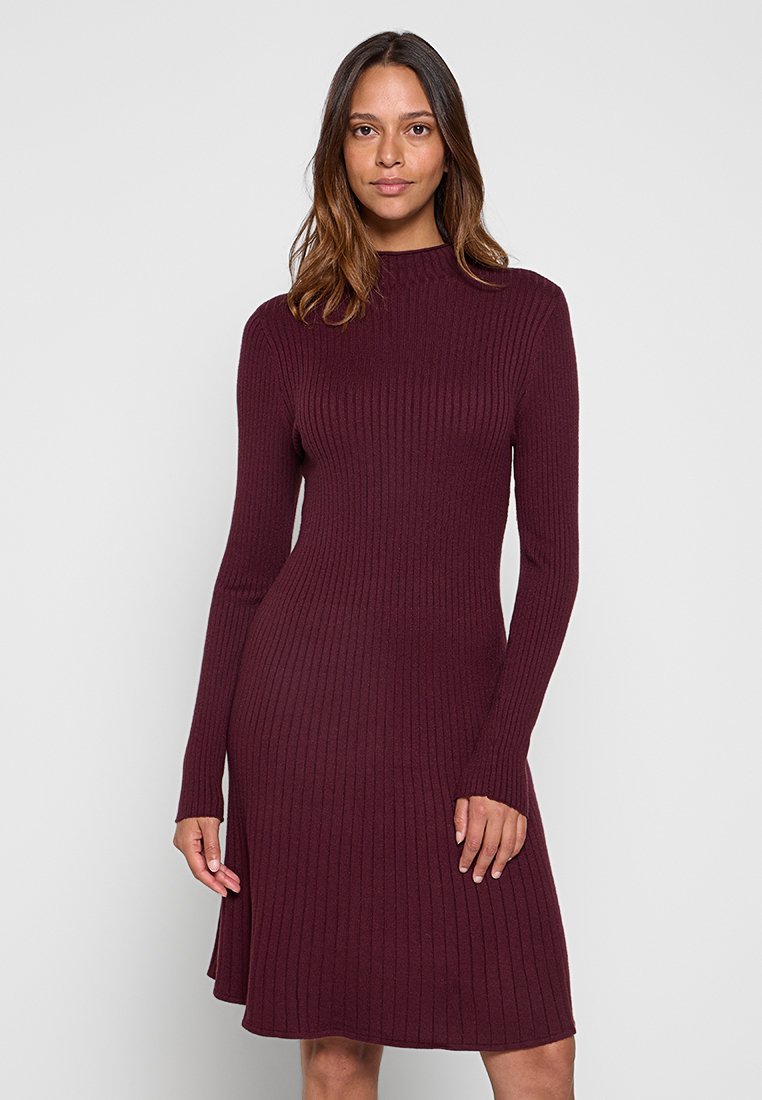 Bordeaux ribbed gebreide jurk met lange mouwen, een hoge halslijn en een uitlopende zoom. Zachte textuur, aansluitend lijfje en een knielange snit.