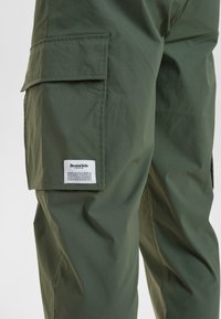 Grønne cargo-bukser lavet af letvægtsstof med en sidelomme, der har et vævet mærke på venstre lår.