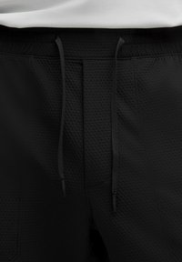 Crne atletske kratke hlače s teksturiranim materijalom, elastičnim pojasom s podesivim vezicama i jednostavnim, funkcionalnim dizajnom.