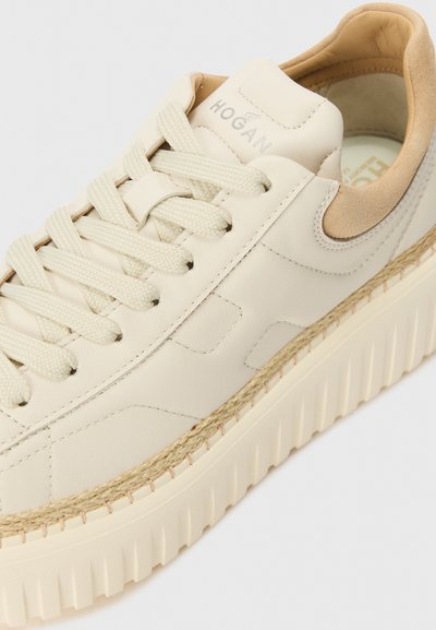 Baskets en cuir beige avec une semelle plate-forme épaisse, accent en corde texturée et lacets plats assortis. Doublure en tan doux visible au niveau du talon.