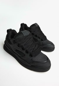 Adidași negri cu un exterior sintetic neted, șireturi texturate, vârf perforat, accente din plasă și talpă din cauciuc. Design minimalist, culoare complet neagră.