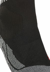 Calzino sportivo nero con tessuto testurizzato, dotato di dettagli grigi e di un logo rosso, forma affusolata progettata per una vestibilità aderente attorno alla caviglia.