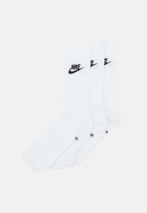 Calcetines blancos de Nike con textura acanalada, que presentan un logo negro en el puño. Se venden en un paquete de tres pares.
