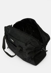 Saco de lona preto com fecho de correr, alças duplas e bolso exterior. O interior possui um forro suave e compartimentos organizacionais.