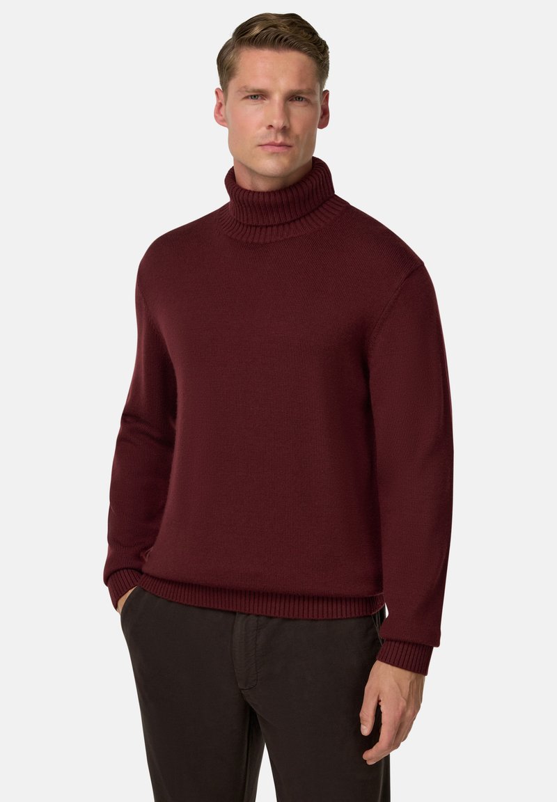 Pull à col roulé bourgogne en tricot côtelé, doté de manches longues et d'une coupe décontractée, associé à un pantalon sombre.