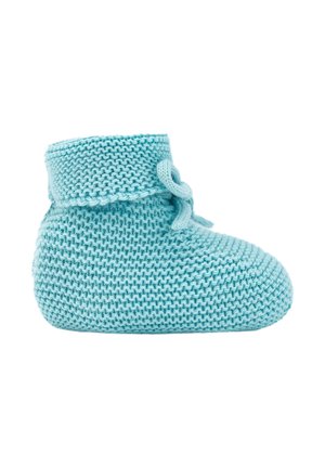 Chausson bébé tricoté bleu clair avec bord replié et nœud noué sur fond blanc.