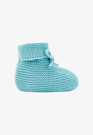 Chausson bébé tricoté bleu clair avec bord replié et nœud noué sur fond blanc.
