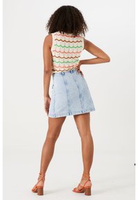 Gebreid tanktop met een zigzagpatroon in oranje, groen en bruin; lichtblauwe denim A-lijn rok; oranje sandaaltjes met bandjes; textuurstof.