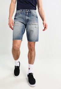 Denim shorts in light blue, featuring a distressed design with rips. Classic cut, standard pockets, and a hem just above the knee.