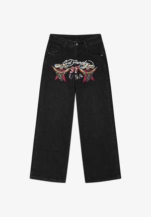Černé džíny s širokými nohavicemi, předními kapsami, knoflíkem a grafickým potiskem se dvěma býčími hlavami a nápisem "Ed Hardy 97 USA" v červené, bílé a žluté barvě.