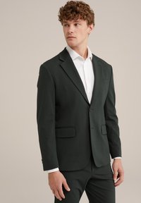 Blazer verde închis, realizat dintr-un material texturat. Prezintă un închidere cu un singur buton, rever tăiat și două buzunare frontale cu o croială ajustată.