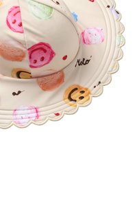 Beżowy kapelusz przeciwsłoneczny z kolorowymi wzorami makaroników i uśmiechniętych buziek, z falbaniastym brzegiem i przeszyciami. Materiał wydaje się gładki i lekki.