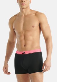 Czarne bokserki z różowym, teksturowanym pasem w talii z logo Adidas. Fason dopasowany, wykonany z gładkiego, elastycznego materiału.