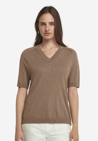 Brun kortärmad V-ringad tröja gjord av ett mjukt, strukturerat material; har en avslappnad passform och ribbade detaljer vid kragen och ärmsluten.