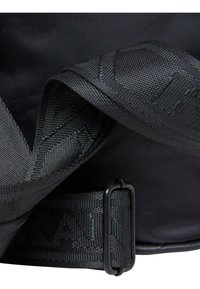 Crni najlon remen za torbu s teksturiranim uzorkom i crnim metalnim kopčanjem. Glatka pozadina od tkanine naglašava dizajn remena.