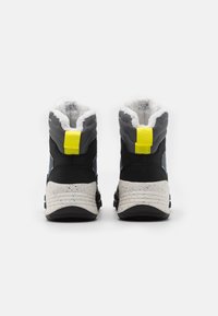 Bottes noires et grises avec une doublure blanche moelleuse, un tirant jaune au niveau du talon et une semelle blanche tachetée. Design montante pour chaleur et soutien.