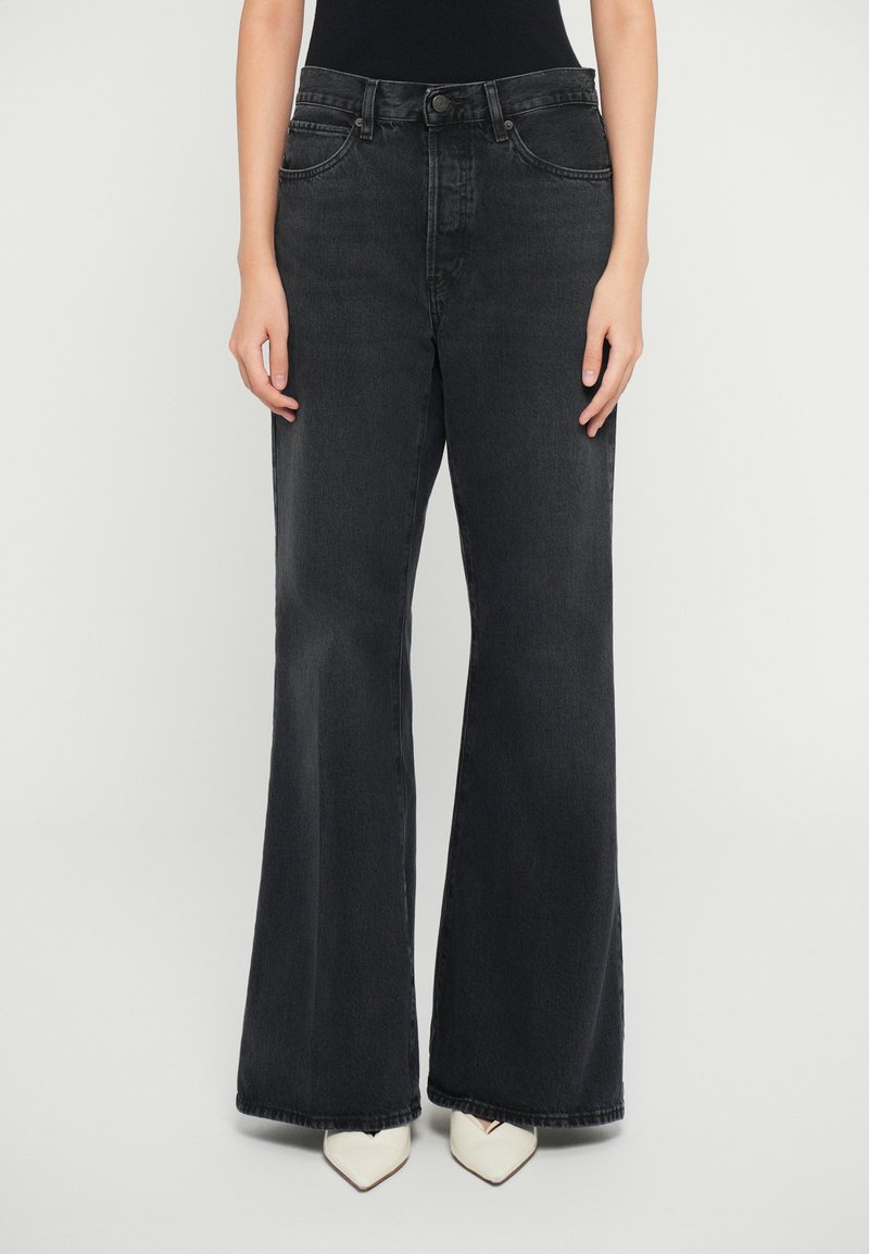 Sorte vidde jeans i denim med høj talje, fem lommers design og sømdetaljer. Sammen med spidse hvide hæle.