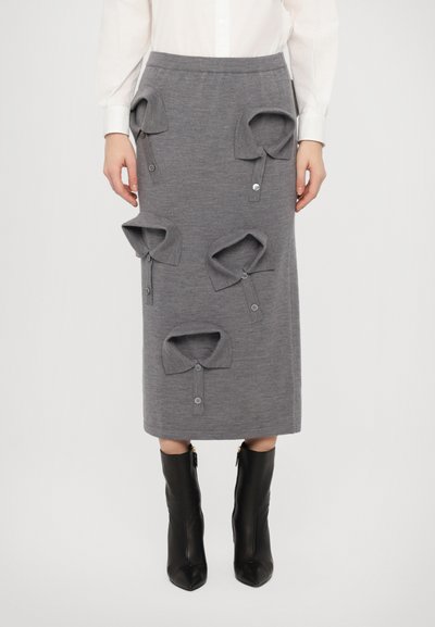 Šedá pletená midi sukně s oversized límcem a knoflíky, elastickým pasem a hladkým povrchem. V kombinaci s černými zipovými kozačkami.