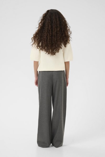 Pull en tricot crème, oversize, à manches courtes associé à un pantalon gris taille haute et large. Texture douce, design minimaliste.