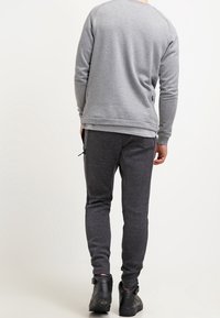 Grijze sweatshirt met een ronde hals en lange mouwen, gecombineerd met donkergrijze joggerbroeken met een gestructureerd patroon en zijzakken.
