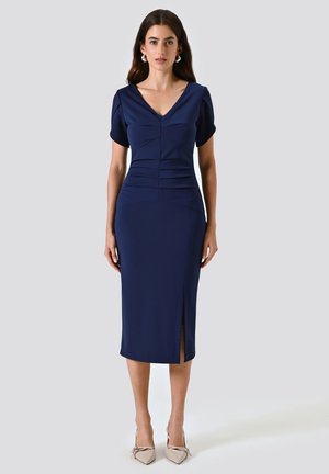 Robe marine midi avec des manches courtes bouffantes, décolleté en V plongeant, buste froncé et fente à l'avant. Tissu à texture lisse, silhouette ajustée.