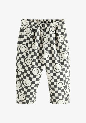 Mustvalged ruudulised püksid, millel on elastne vöökoht ja mis on kaunistatud võrdselt paigutatud mustade naerunägudega valgetel ruutudel.