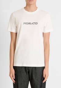 Camiseta de algodón blanca con la palabra "MORATO" impresa en una fuente negrita de color gris oscuro en el pecho; cuello redondo sencillo y mangas cortas.