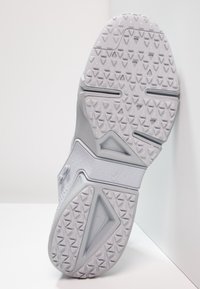 Ljusgrå Nike-sneakersula med ett texturerat mönster, triangulära spår och framträdande varumärke präglat på sidan.