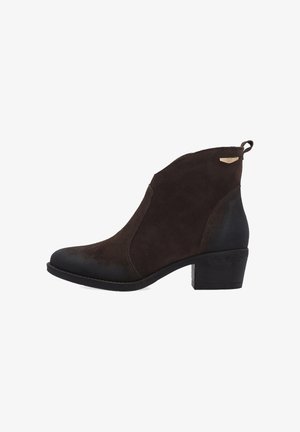 Brun ruskindsankelstøvle med en glat sort tåhætte, lav blokhæl, elastiske sidepaneler og en træktab bagpå for nem påklædning.