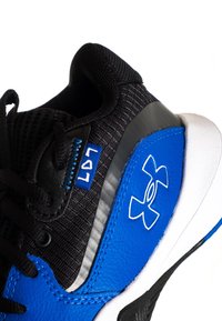 Zapatilla deportiva negra y azul con un material superior texturizado, detalles en cuero, una suela blanca y un detalle de logo. Diseño con cordones y costuras reforzadas.