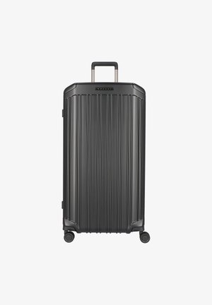 Valise rigide noire avec des rainures verticales, poignée rétractable et quatre roues. Texture lisse avec des accents en métal et un logo sur le dessus.