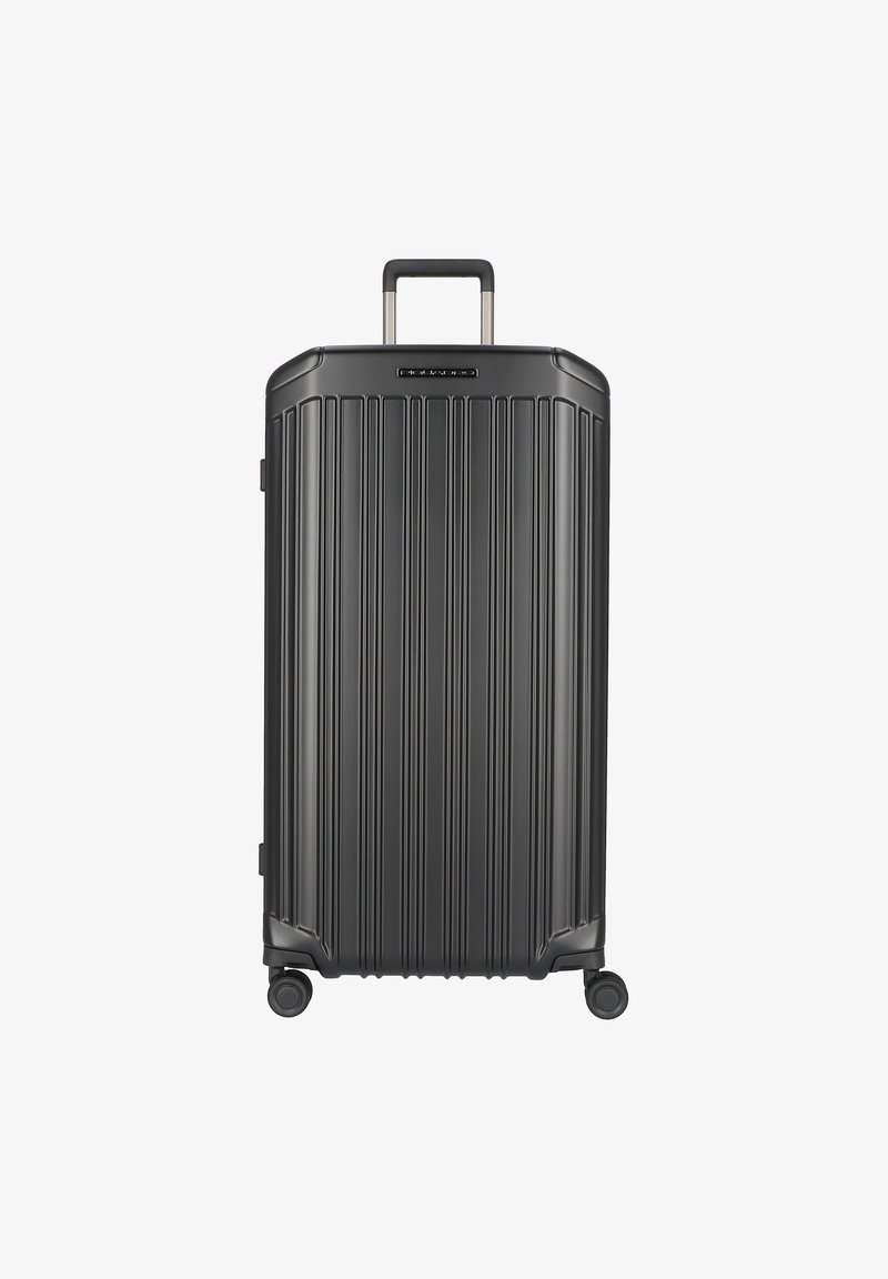 Valigia rigida nera con scanalature verticali, manico retrattile e quattro ruote. Texture liscia con dettagli metallici e logo sulla parte superiore.
