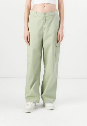 Light green cargo pants made of cotton with a relaxed fit, featuring side pockets and a button closure. Worn with white sneakers.