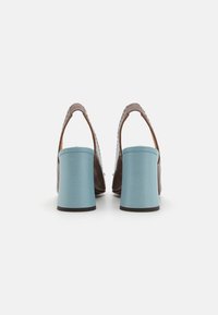 Hnědé kožené slingback boty s texturovaným svrškem a širokými světle modrými blokovými podpatky, s nastavovací patní páskou a otevřeným designem vzadu.