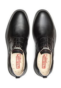 Chaussures en cuir noir avec une pointe arrondie, texture lisse et un design à lacets. L'intérieur possède une semelle perforée avec un logo rouge.