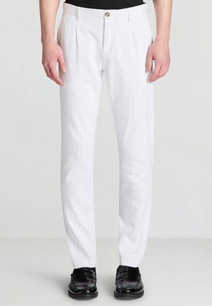 White pinstriped trousers made from a lightweight fabric, featuring a tailored fit, front pleats, and a single button closure. Black shoes are worn.