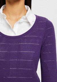 Pull violet tricoté avec un col rond, présentant des motifs texturés alternés et de petites mailles ouvertes sur tout le tissu.