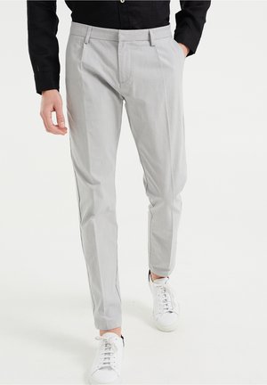 Jasnoszare, prążkowane spodnie o slim fit, z płaskim przodem i bocznymi kieszeniami, w połączeniu z białymi sneakersami.