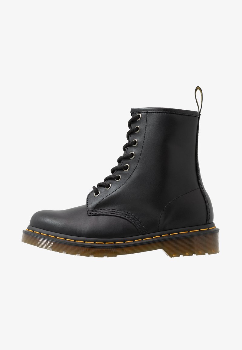 Botín de cuero negro con punta redonda, diseño de cordones con ojales, costuras naranjas y suela chunky translúcida. Lleva un tirador en la parte trasera.