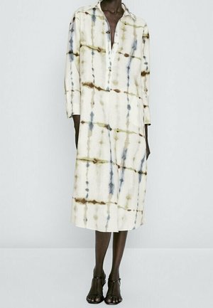 Robe longue à col en crème avec des motifs tie-dye vert et bleu. Confectionnée dans un tissu léger, elle dispose d'une patte de boutonnage et de manches longues.