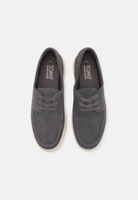 Scarpe in suede grigio con dettagli lacciati, suola a contrasto color crema e cuciture sobrie. Presentano una soletta con logo. Design casual classico.