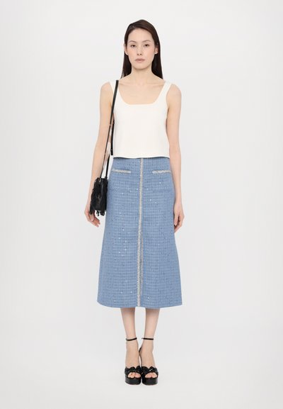 Valge lühike spagetihälu tank top, sinine tweed midi seelik hõbedaste detailidega ja mustad sandaalid kaunistustega. Mudel kannab musta fraktsiooniga kotti.