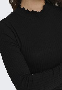Svart ribbete halsen topp med flared halslinje og lange ermer, som viser et strukturert stoff og tettsittende design.
