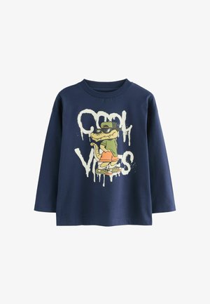Marineblauw langemouwen T-shirt met een afbeelding van een cartoon krokodil in een pet, met de tekst "Cool Vibes" in witte, druipende verfstijl.