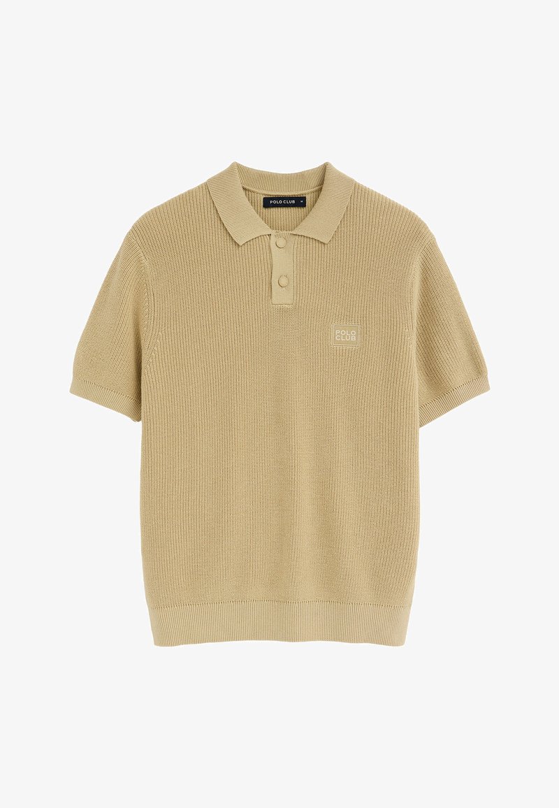 Polo en maille beige à manches courtes avec col, deux boutons et un écusson logo "Polo Club" sur la poitrine gauche.