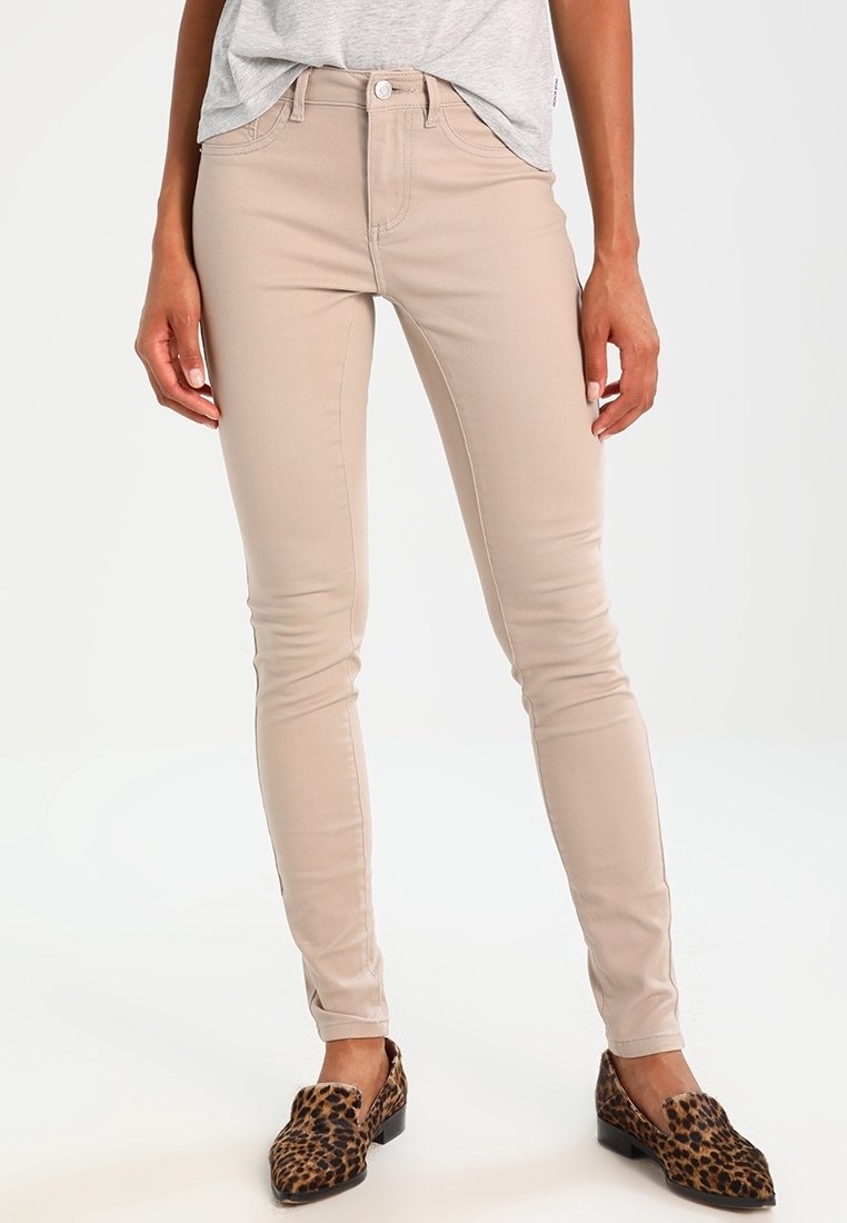 Jeans skinny beige in denim, con un classico design a cinque tasche, chiusura anteriore con bottone e dettagli di cucitura a contrasto.