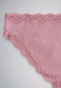 Rosa bomuldsundertøj med blomsterblondekant langs linningen og benåbninger på en neutral baggrund.
